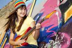 美丽的浅黑肤色的女人女孩吉他涂鸦墙后台支持