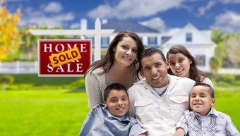 拉美裔家庭前面出售真正的房地产标志房子