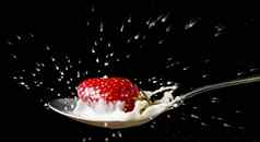 红色的成熟的草莓下降勺子牛奶