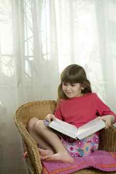 可爱的女孩年阅读书坐着