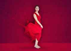 快乐亚洲女人红色的衣服把油漆飞溅