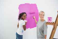 微笑年轻的室友绘画墙粉红色的