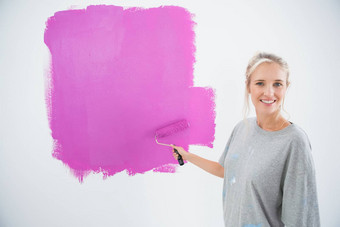 快乐年轻的女人绘画墙粉红色的
