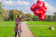 年轻的快乐有吸引力的女人美丽的衣服有趣的红色的气球