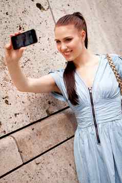 有吸引力的年轻的女人智能手机相机照片户外
