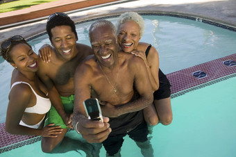 高级夫妇中年人夫妇摆姿势移动电话照片游泳池升高视图