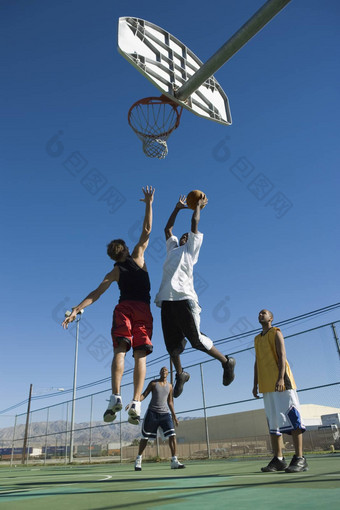 低角视图多民族朋友玩<strong>篮球</strong>清晰的蓝色的<strong>天空</strong>