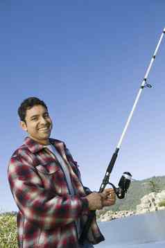 肖像快乐拉美裔男人。钓鱼附近的湖