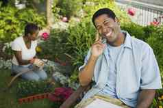 肖像非洲美国男人。微笑女人浇水植物背景