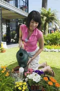 快乐亚洲女人浇水花花园