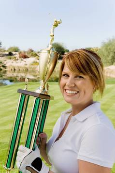 肖像快乐女高尔夫球手持有奖杯高尔夫球