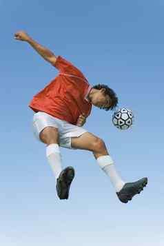 低角视图足球运动员标题球清晰的天空
