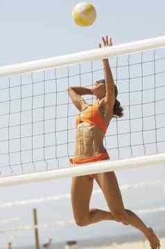 女海滩排球球员跳斯派克排球网