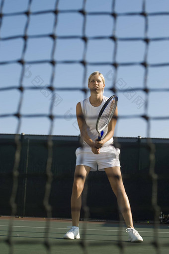 年轻的女人网球球拍站网