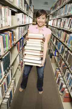 完整的长度肖像女大学学生携带堆栈书图书馆