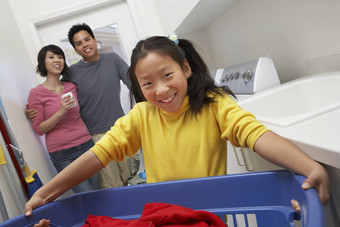 肖像快乐十几岁的女孩持有洗衣篮子父母背景