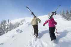 后视图夫妇滑雪板徒步旅行雪坡