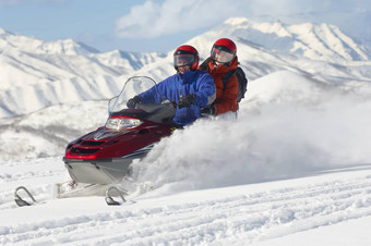多民族夫妇骑电动机雪橇雪
