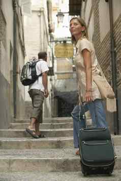 快乐中间岁的女人行李移动楼上小巷男人。背景