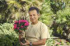 肖像快乐男人。持有花植物花园