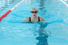 年轻的女人游泳室内池breastroke风格