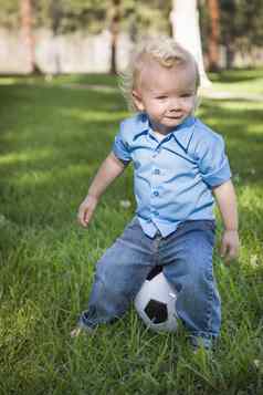 年轻的可爱的男孩玩足球球公园