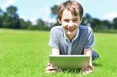 年轻的男孩平板电脑设备草原