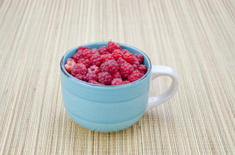 新鲜的树莓水果蓝色的陶瓷杯