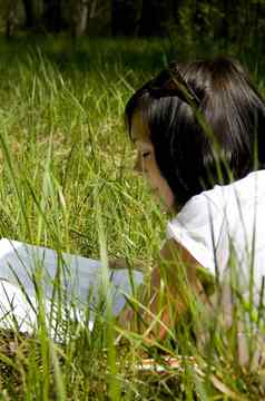 漂亮的年轻的女孩阅读草