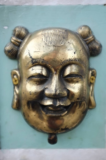黄铜青铜中国人面具绿色水泥墙