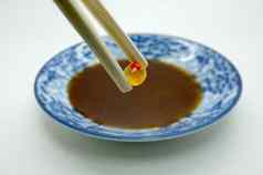 筷子捏红色的鱼子酱大马哈鱼罗伊芥末酱酱汁