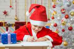 女孩穿着圣诞老人老人写作列表想要的礼物圣诞节