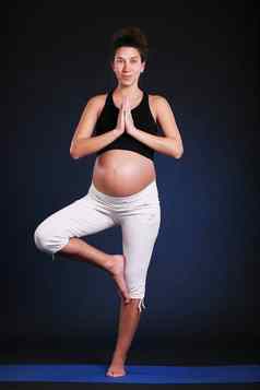 美丽的怀孕了年轻的女人练习瑜伽