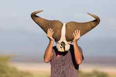 男人。持有大非洲水牛头骨穿面具自然非洲野生动物Safari