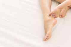 女人手持有脚踝疼痛白色床上健康护理