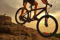 骑自行车的人骑山自行车岩石日落极端的体育运动复古骑自行车概念