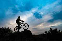 轮廓骑自行车的人山自行车岩石日落极端的体育复古骑自行车概念