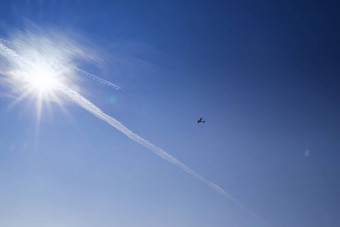 蓝色的天空背景蓝色的天空明亮的太阳飞机飞行飞机飞行天空背景明亮的日落基本背景设计