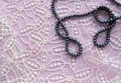 躺平粉红色的背景华丽的花边闪闪发光的项链黑色的珍珠时尚的手镯美时尚概念