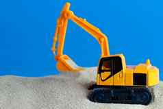 黄色的玩具反铲挖掘沙子蓝色的背景re
