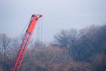 <strong>建设过程建设</strong>汽车起重机红色的Gibbet秋天雾河桥模糊背景森林起重机