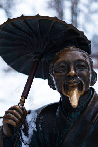 青铜纪念碑中国人男人。伞冬天雪公园特写镜头模糊背景