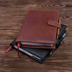 棕色（的）黑色的手工制作的皮革笔记本涵盖了笔记本笔内部木背景股票照片奢侈品业务配件