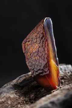 自然琥珀色的一块黑暗红色的半透明的自然琥珀色的一块用石头砸木