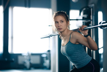 有吸引力的年轻的体育女人<strong>下蹲</strong>杠铃健身房健身健康的生活方式