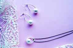 美丽的银闪亮的珍珠珠宝时尚的霓虹灯发光时尚的迷人的耳环链粉红色的紫色的背景精致的花边平躺
