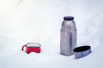 红色的金属杯咖啡倒热水瓶纯白色雪森林走