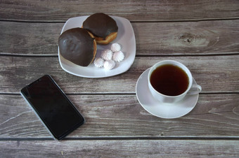 杯黑色的茶飞碟板甜甜圈巧克力糖衣块我们说谎木表格墙智能手机咖啡打破特写镜头