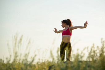 女人伸展运动户外温暖的锻炼夏天晚上体育运动健康的活跃的生命系统概念