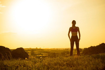 女人伸展运动户外温暖的锻炼日落体育运动健康的活跃的生命系统概念